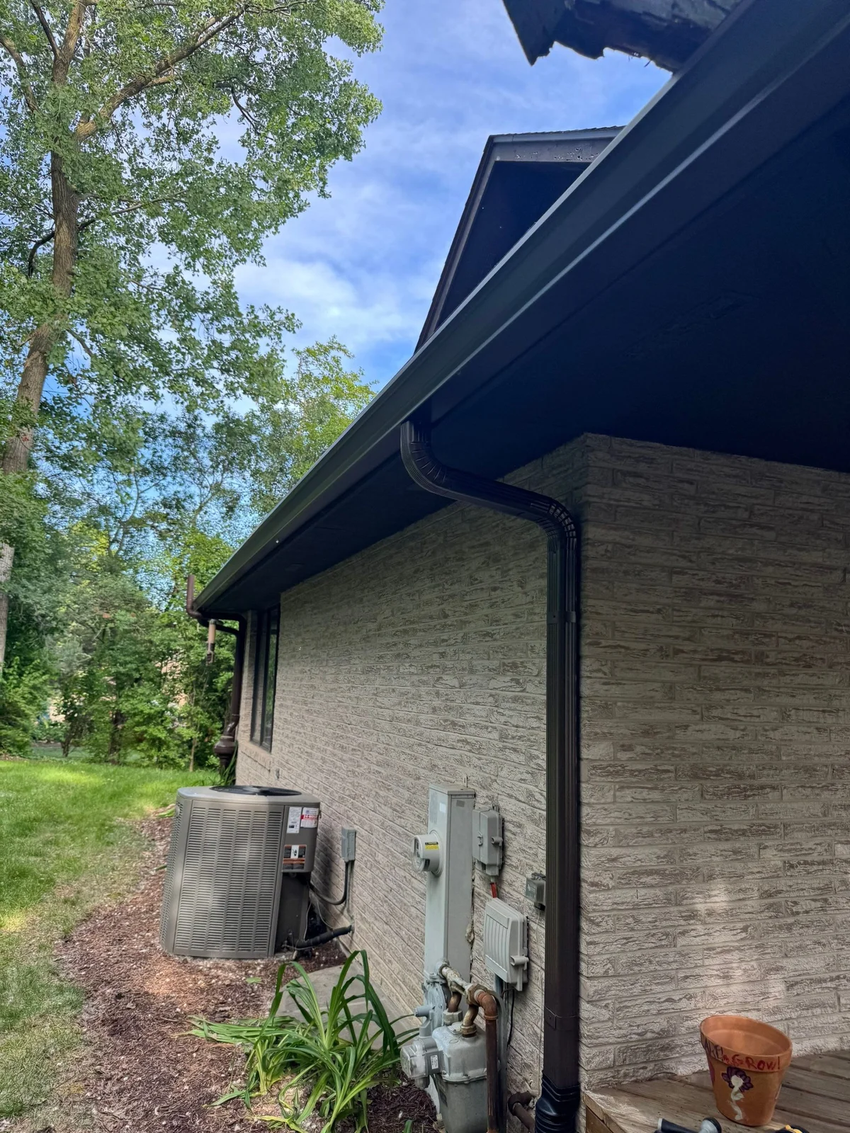 Black gutters and downspouts fitted along a brick home in Lockport, Illinois